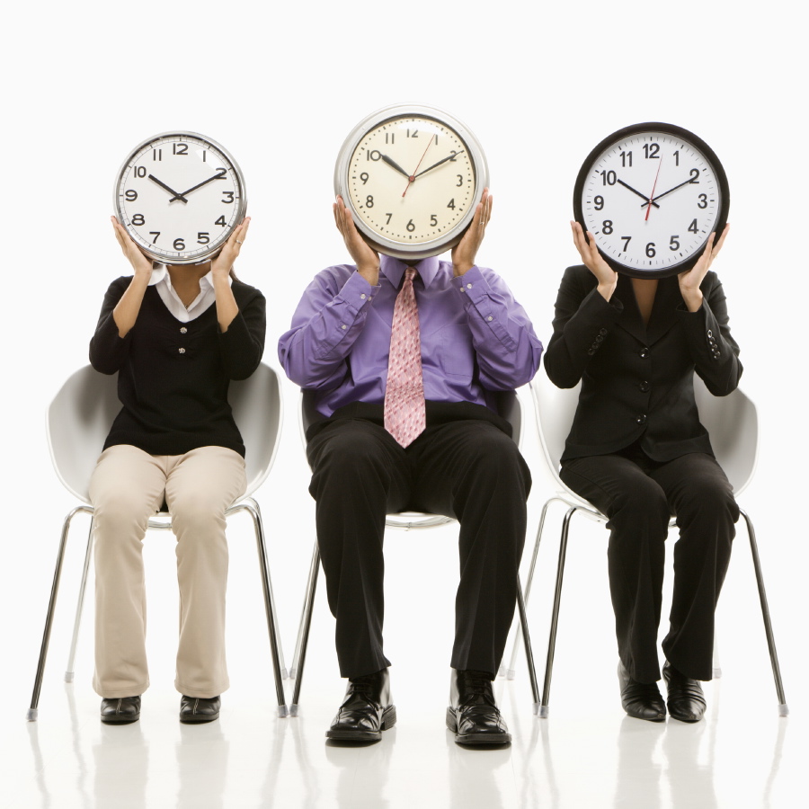 Business people holding clocks over their faces